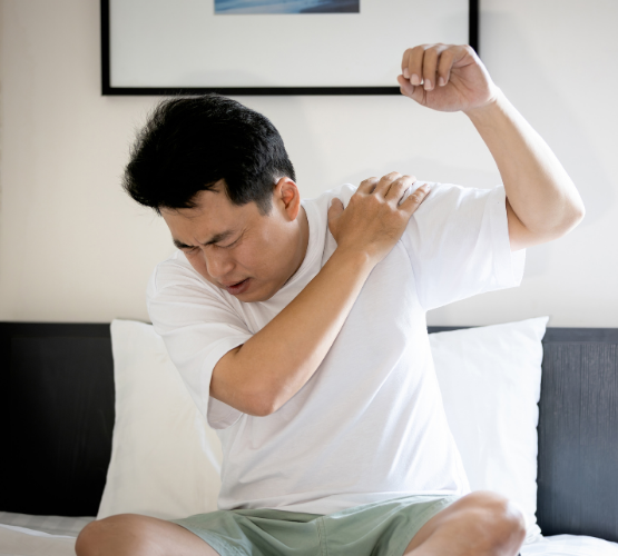 腕を上に挙げたときに肩関節に痛みが生じて肩を押さえている人の様子